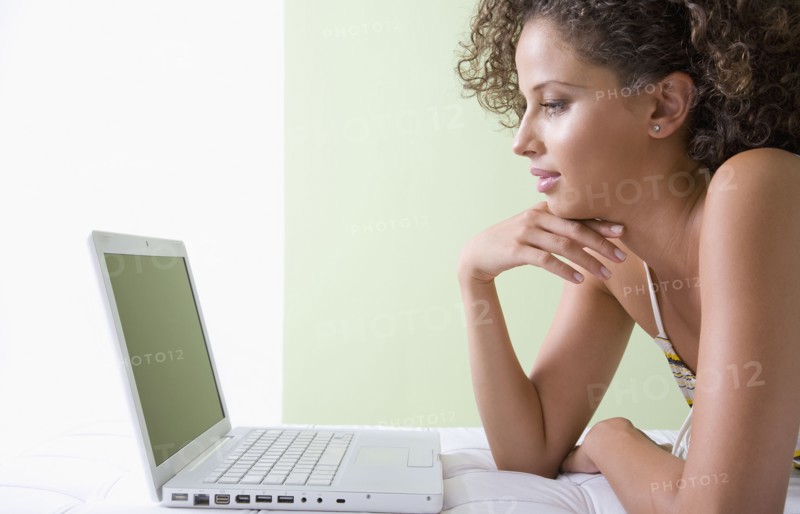 Mixed race woman laying on sofa using laptop
