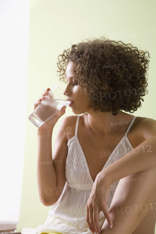 Mixed race woman drinking glass of water