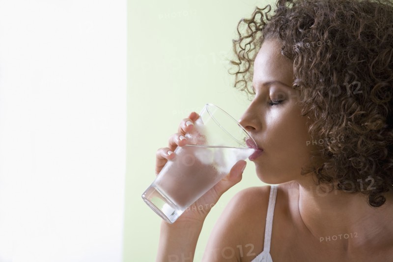 Mixed race woman drinking glass of water