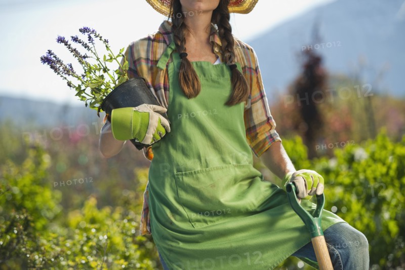 Caucasian woman standing with shovel and flowers in plant nursery
