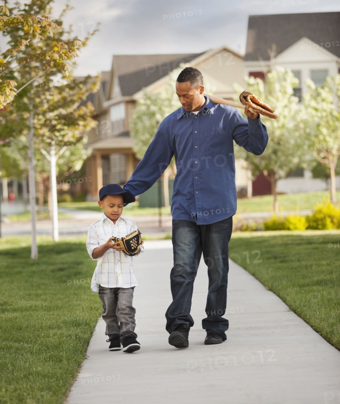 Father and son walking with baseball glove and bat