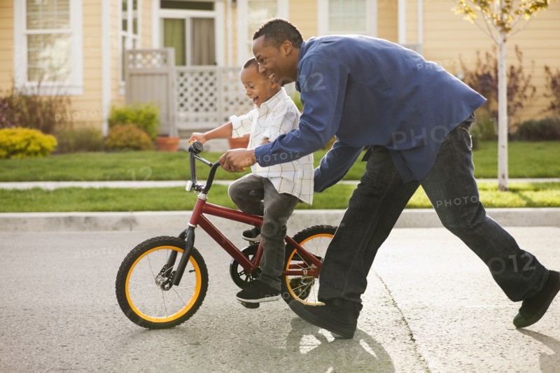 Father teaching son to ride bicycle