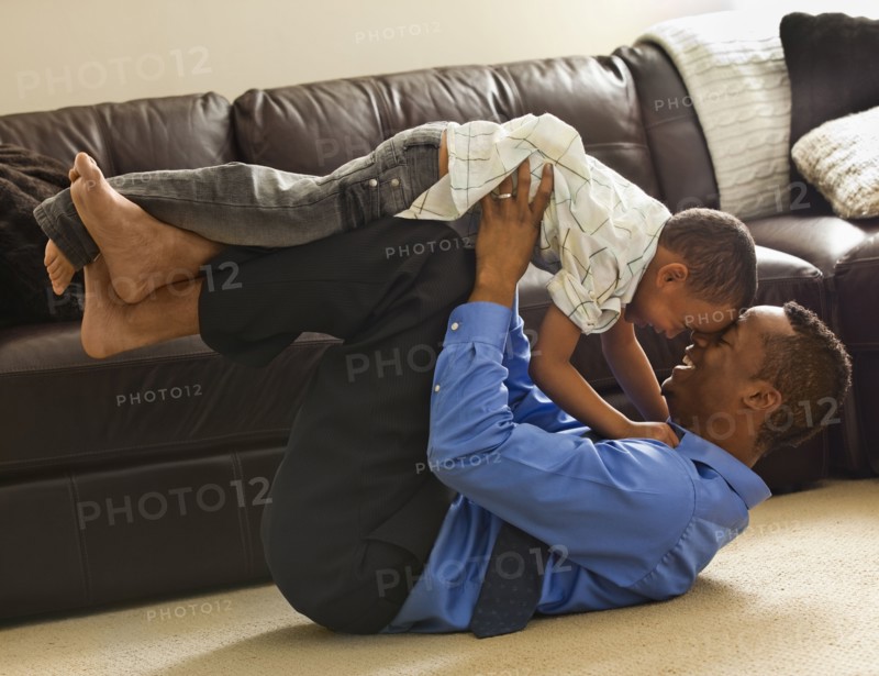 Father playing with son on living room floor
