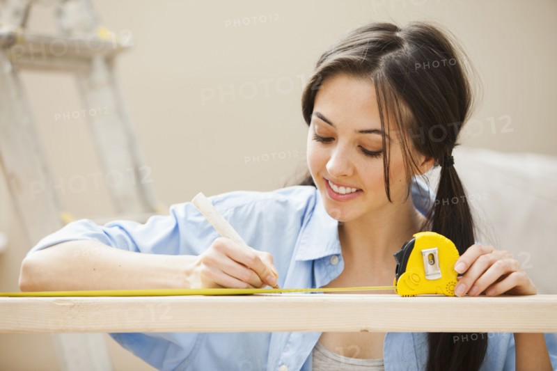 Caucasian woman measuring wood