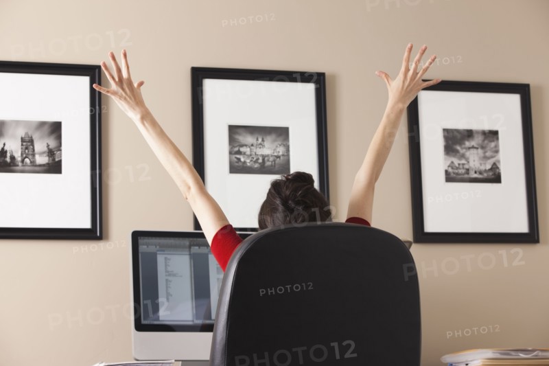 Caucasian woman cheering at desk in home office