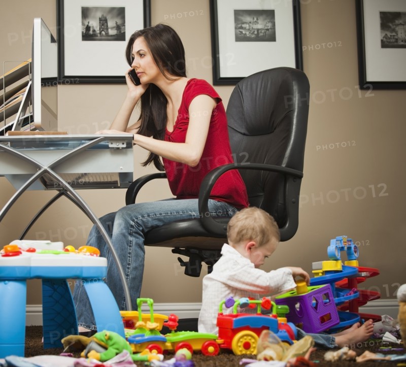 Caucasian woman tending child and working in home office