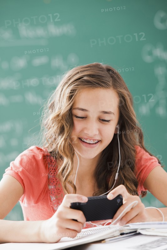 Caucasian teenager listening to mp3 player in classroom