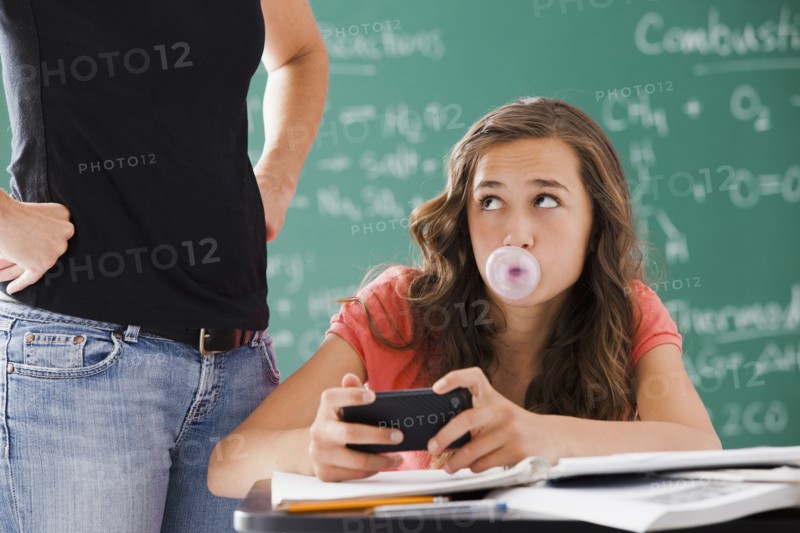 Frustrated teacher watching student with cell phone and gum