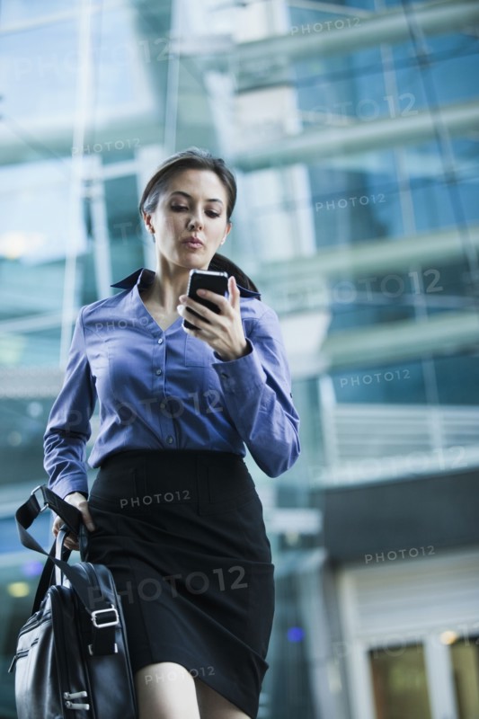 Caucasian businesswoman looking at cell phone outdoors