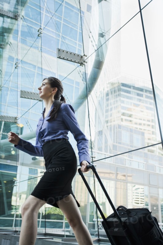 Caucasian businesswoman pulling suitcase outdoors
