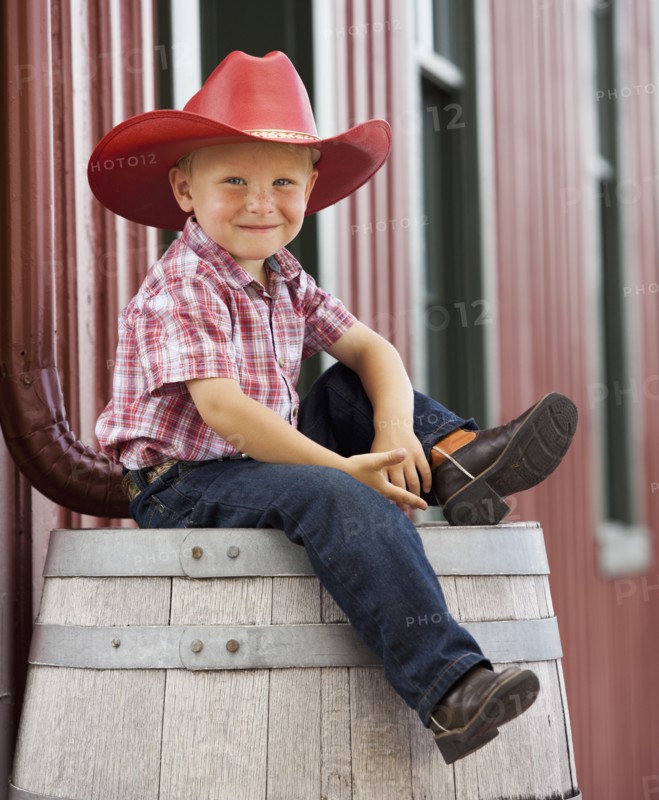 Caucasian cowboy sitting on barrel