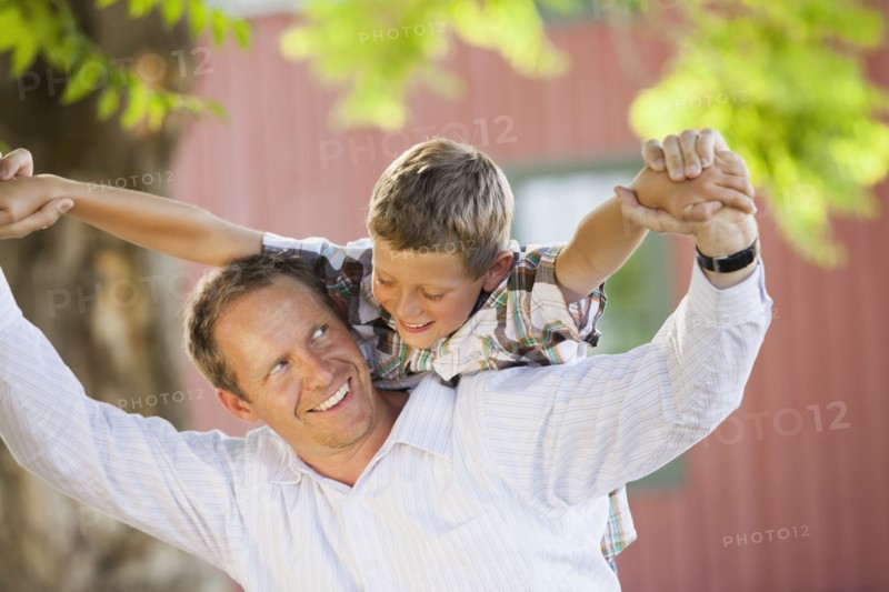 Caucasian father carrying son on his shoulders