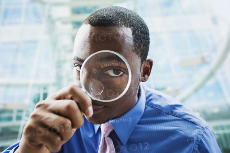 Black businessman using magnifying glass