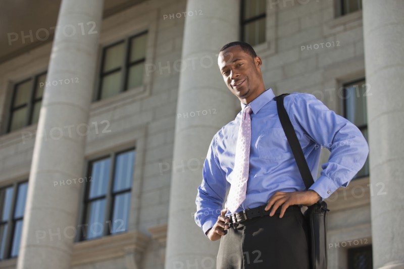 Black businessman standing outdoors with hands on hips