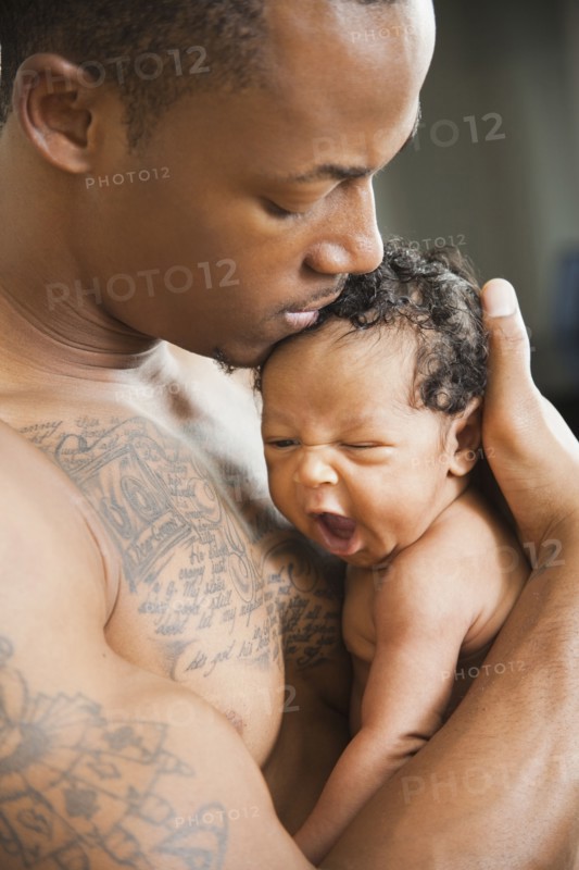 Tattooed father holding newborn baby