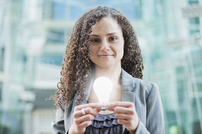 Caucasian businesswoman holding glowing light bulb