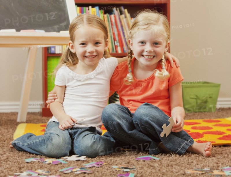 Caucasian sisters putting together puzzle