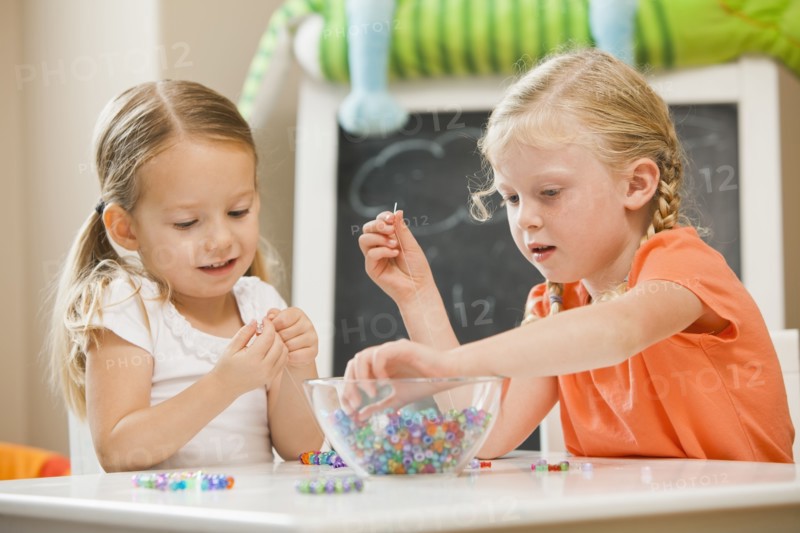 Caucasian sisters playing with beads