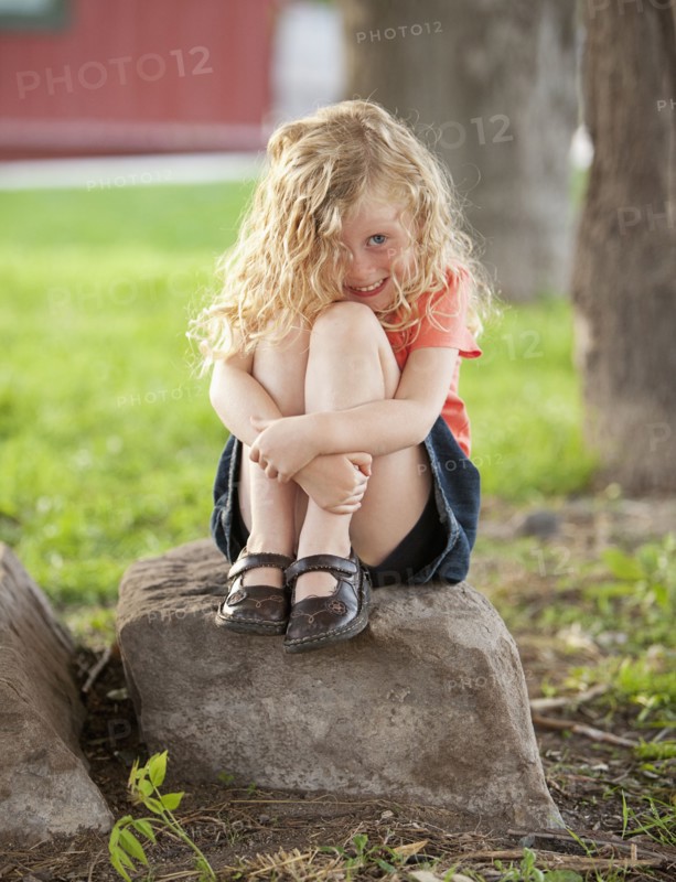 Smiling Caucasian girl sitting on rock