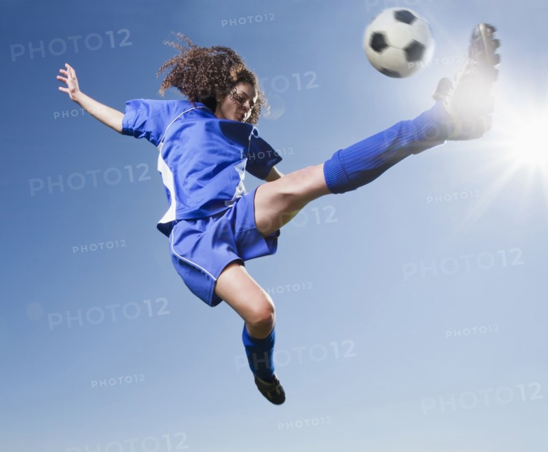 Caucasian woman kicking soccer ball