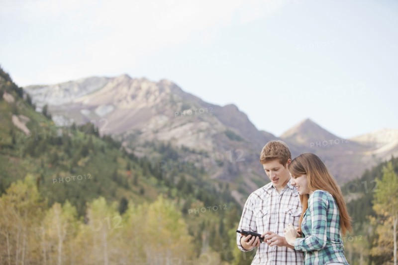 Caucasian couple looking at GPS device in remote area