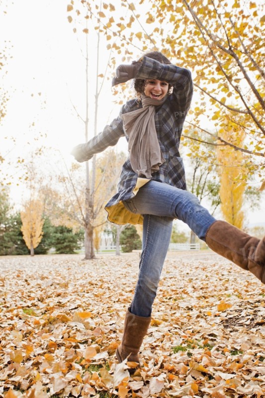 Caucasian woman playing in autumn leaves