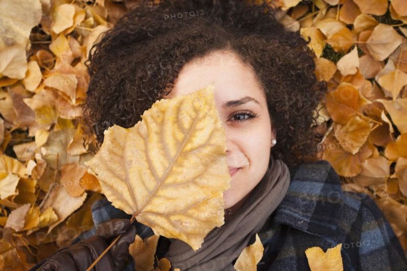 Caucasian woman laying in autumn leaves