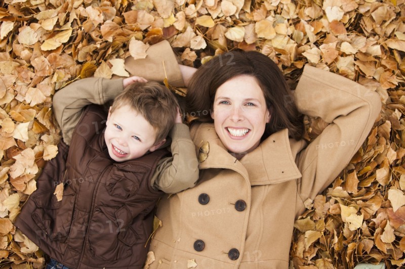 Caucasian mother and son laying autumn leaves