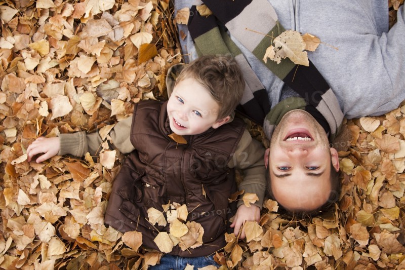 Caucasian father and son laying in autumn leaves