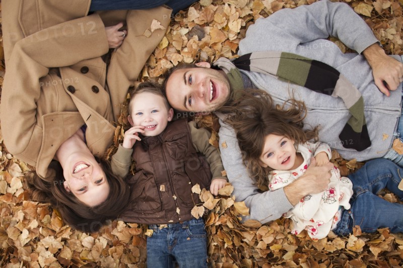 Caucasian family laying in autumn leaves