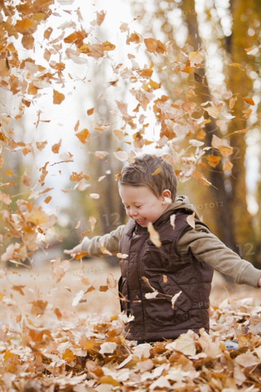 Caucasian boy playing in autumn leaves