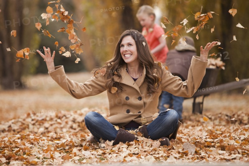 Caucasian woman playing in autumn leaves