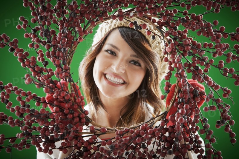 Mixed race woman holding berry wreath