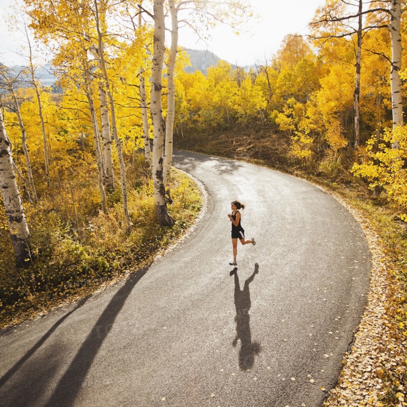Caucasian woman running along autumn road