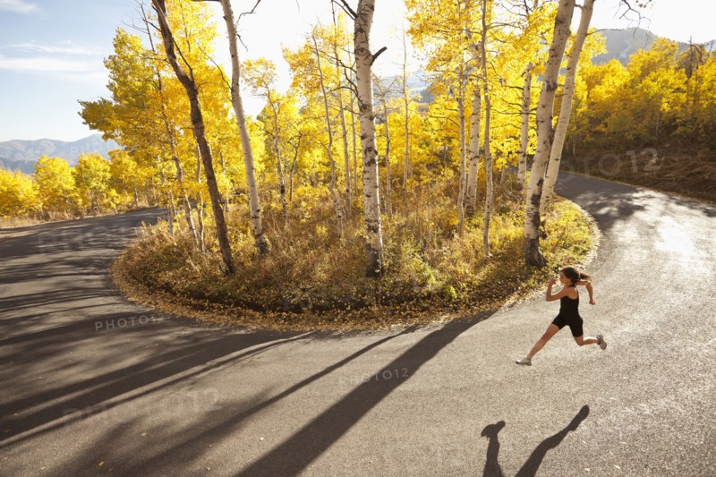 Caucasian woman running along autumn road