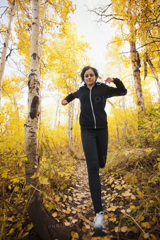 Caucasian woman running in autumn forest