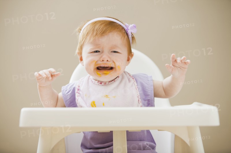Caucasian baby girl crying in high chair