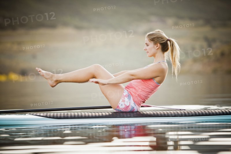 Caucasian woman practicing yoga on paddle board