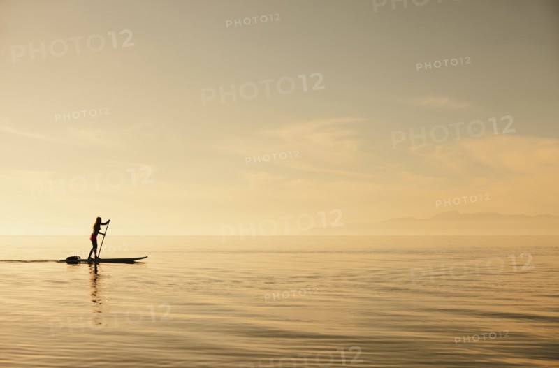 Caucasian woman standing on paddle board