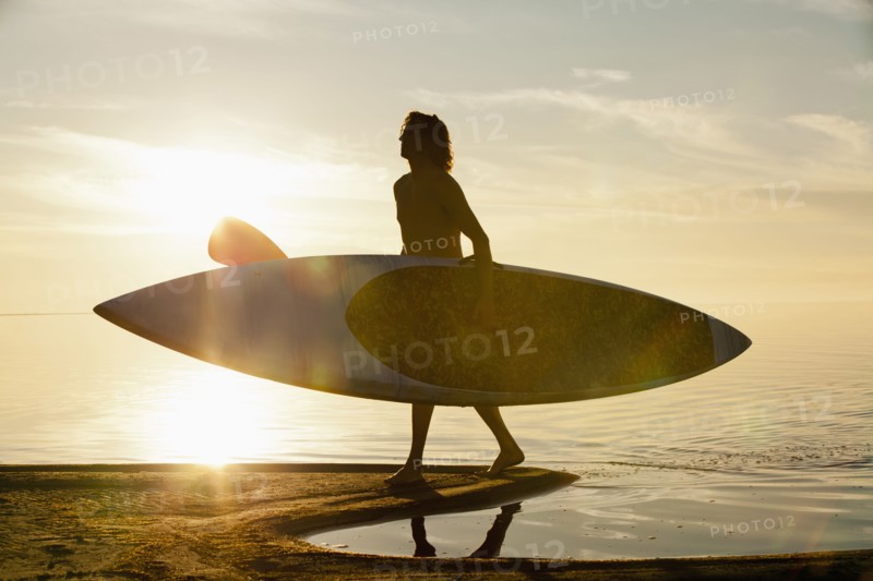 Caucasian man carrying paddle board on beach