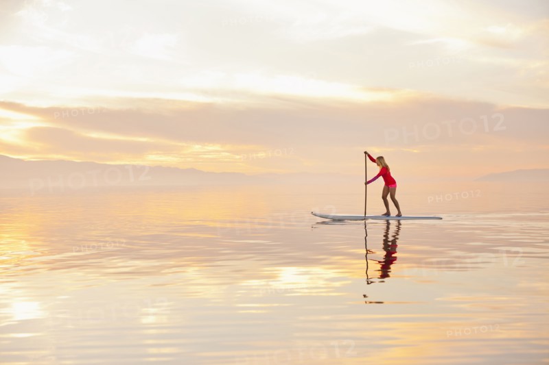 Caucasian woman standing on paddle board