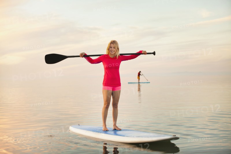 Caucasian woman standing on paddle board