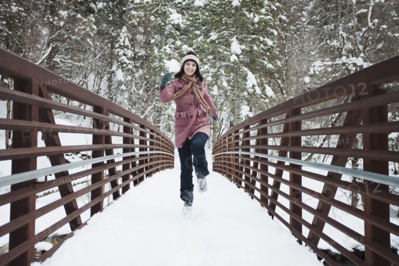 Caucasian woman crossing snow covered bridge
