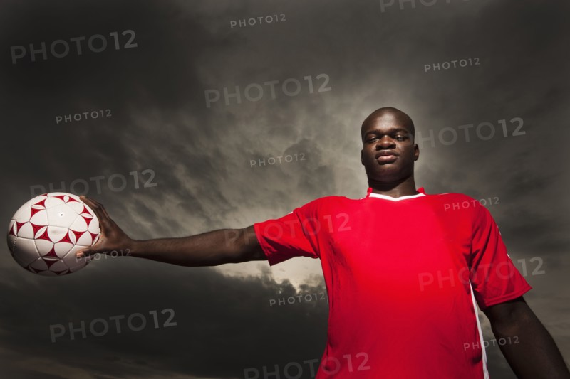Black soccer player holding ball