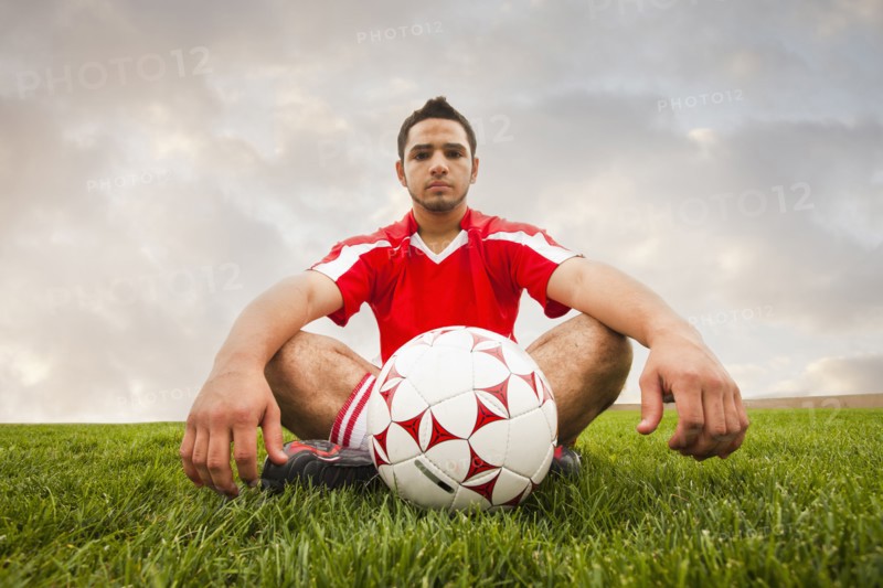 Hispanic soccer player sitting with ball