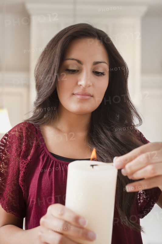 Mixed race woman lighting candle