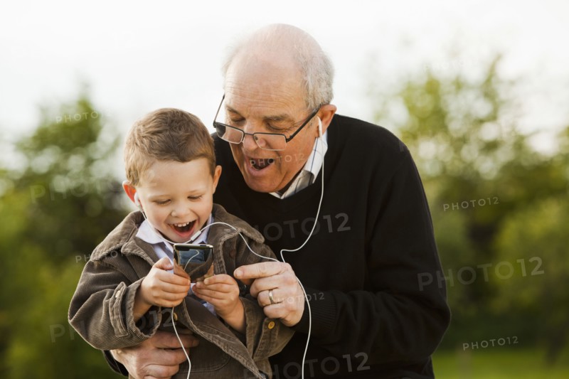 Caucasian grandfather and grandson listening to mp3 player