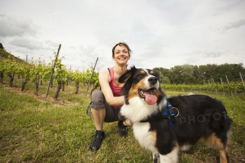 Caucasian woman petting dog in vineyard
