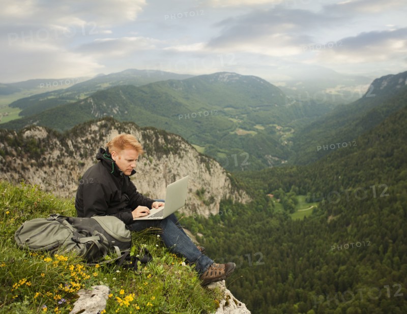 Caucasian man using laptop on remote cliff's edge