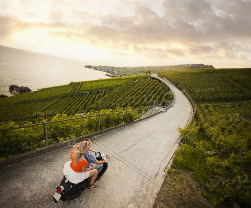 Couple riding scooter in vineyard